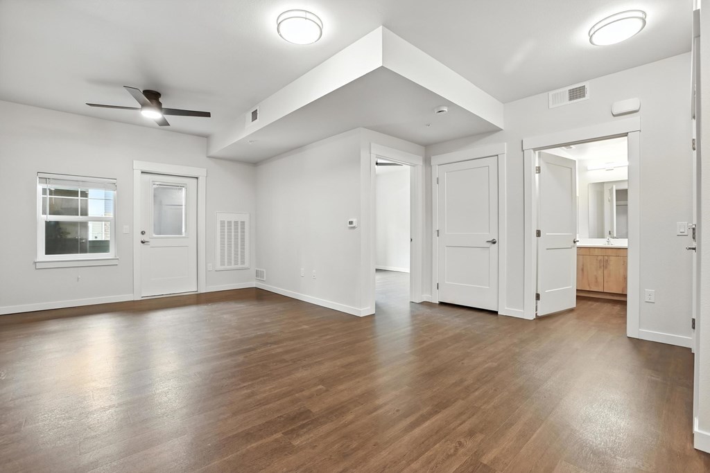 A spacious room with wooden floors and white walls.