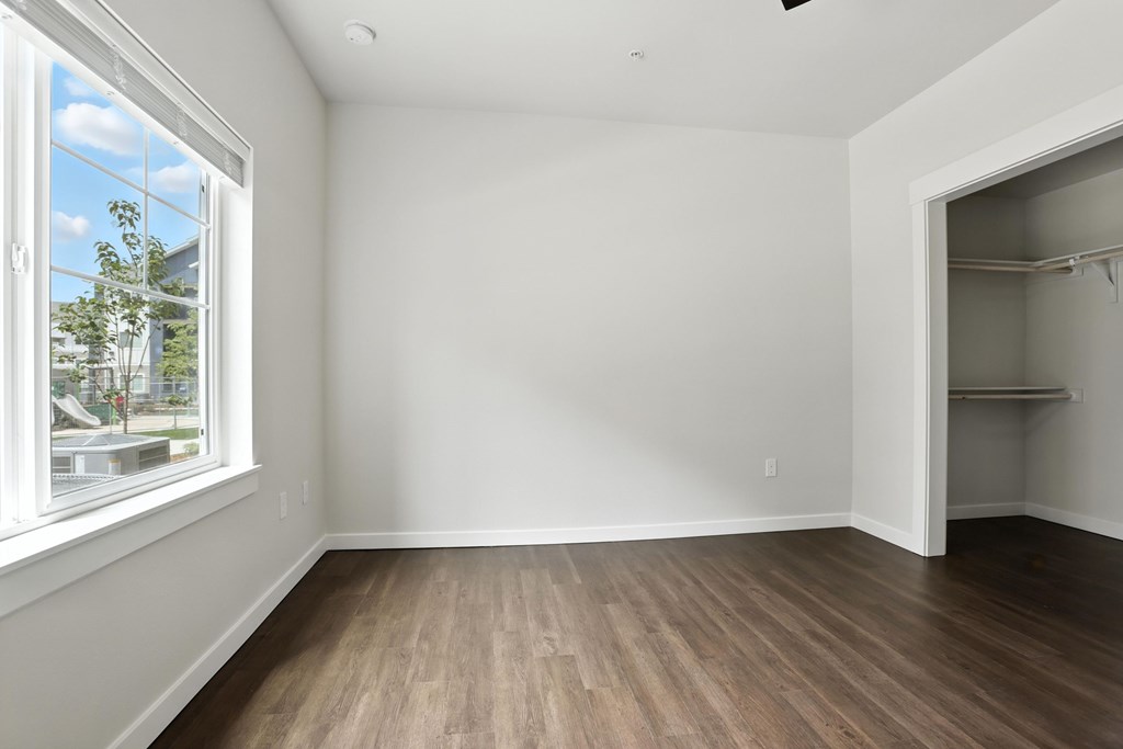 A room with a window and a wooden floor.