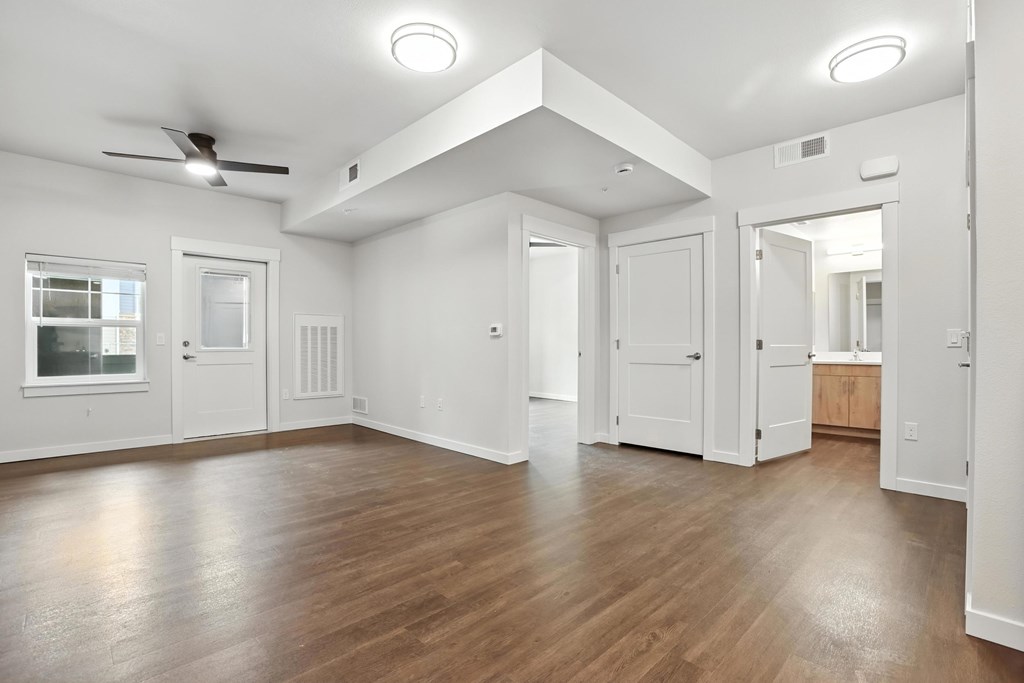 A spacious room with wooden floors and white walls.
