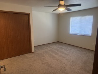 A room with a ceiling fan and a window with blinds.