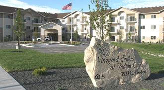 an image showing Vineyard Suites at Indian Creek with US flag and stone monument sign