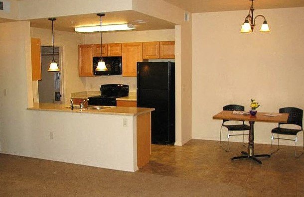 an empty living room with a kitchen and a table
