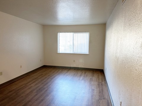 an empty living room with wood floors and a window