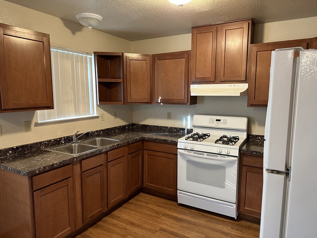 Kitchen showing gas stove, stainless steal sinks and window with blinds