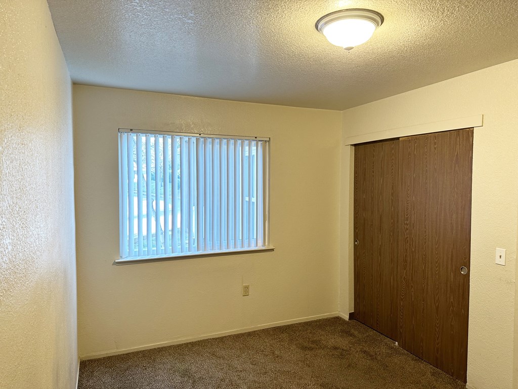 Bedroom with double closet, carpet and window with blinds