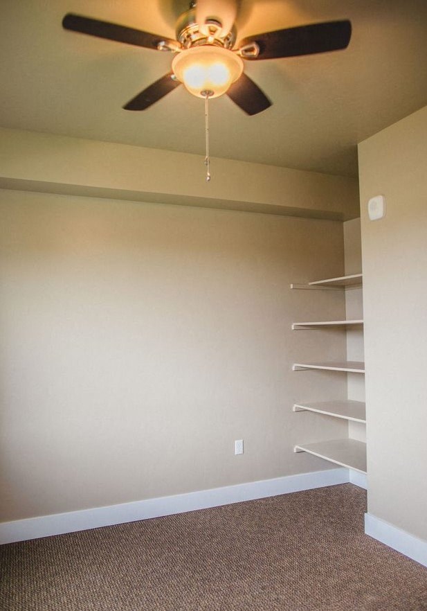 a ceiling fan hanging from a ceiling in a bedroom with shelving