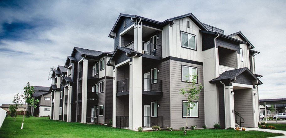 a view of the apartment complex with balconies and green grass