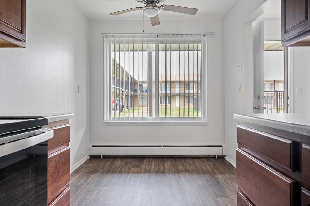 an empty kitchen with a large window and wood flooring