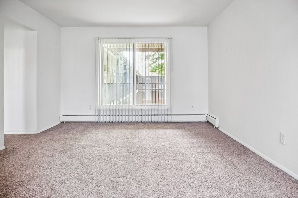 an empty living room with a large window and carpet