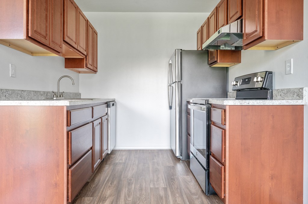 an empty kitchen with wooden cabinets and a stainless steel refrigerator
