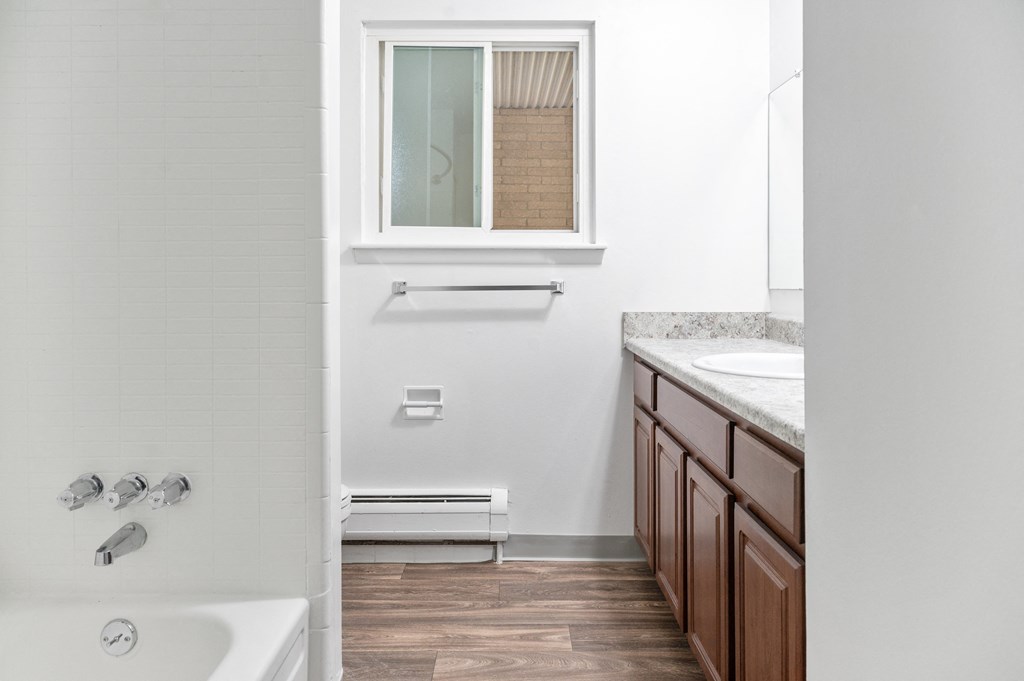 a bathroom with a tub and a sink and a window