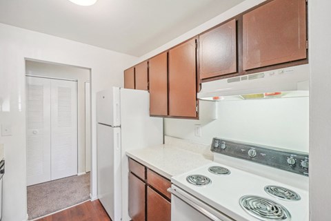 a kitchen with white appliances and wooden cabinets and a refrigerator