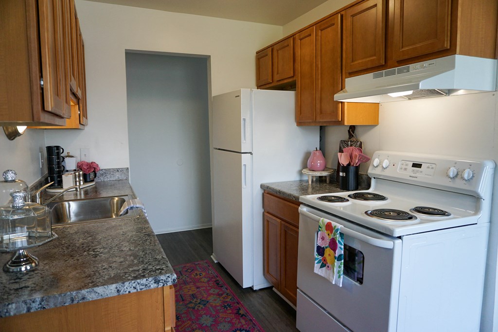 Kitchen with granite countertop, oven, refrigerator, sink, and wood cabinets, at Gale Gardens Apartments,