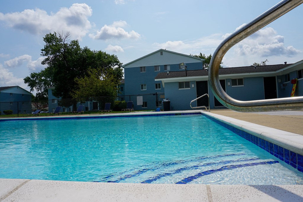 Swimming Pool Entry with pool chairs and apartment building, at Gale Gardens