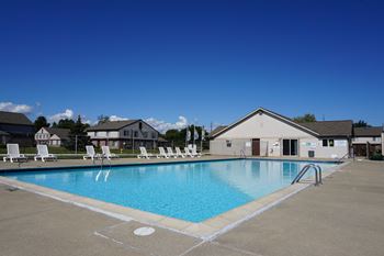 Swimming Pool and pool chairs with apartment in background, at Farmbrooke Manor