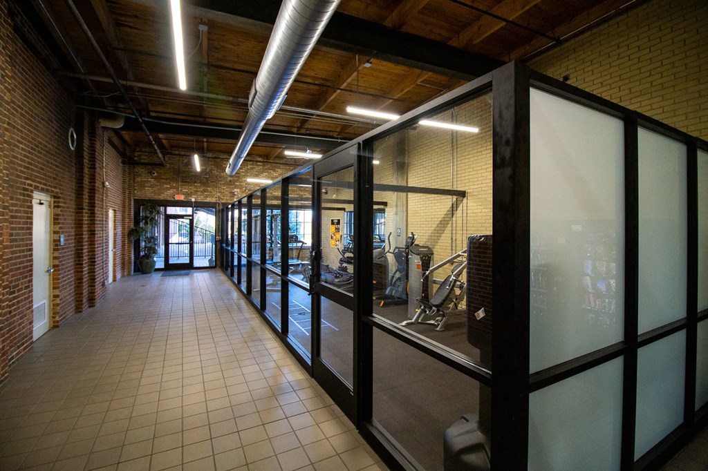 a long corridor with glass walls and a door in the background
