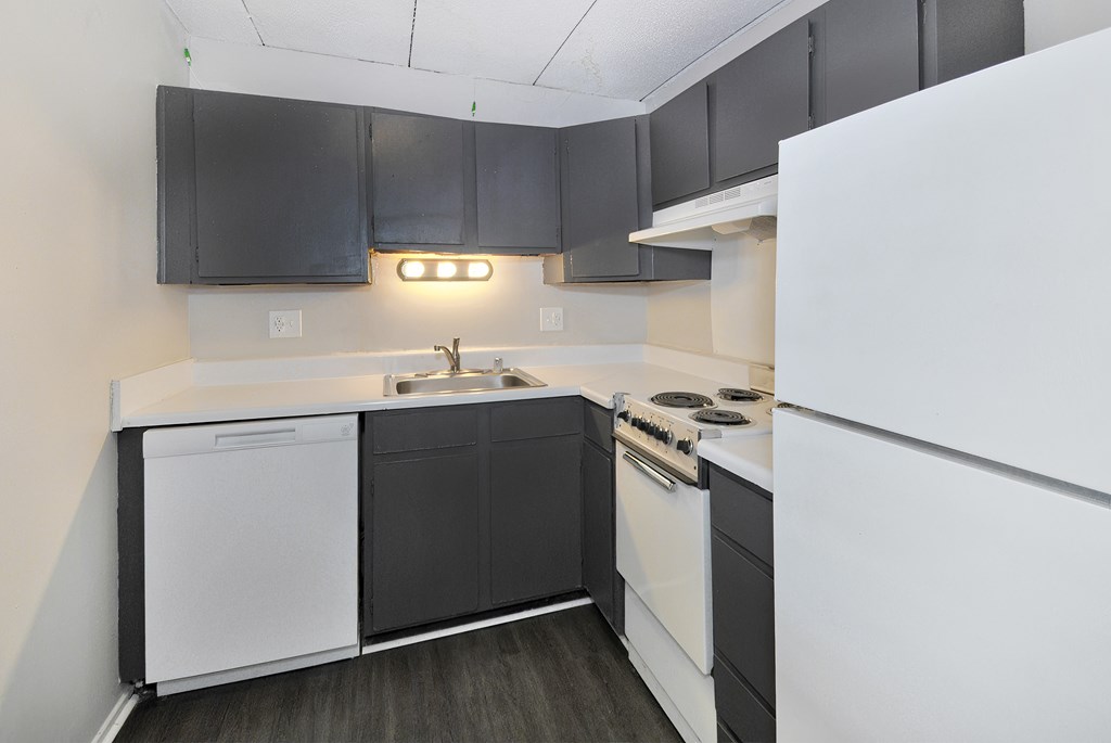 A kitchen with black cabinets and white appliances.