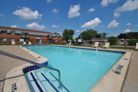 Outdoor swimming pool with sunchairs at Warren Woods Apartments in Warren, MI.