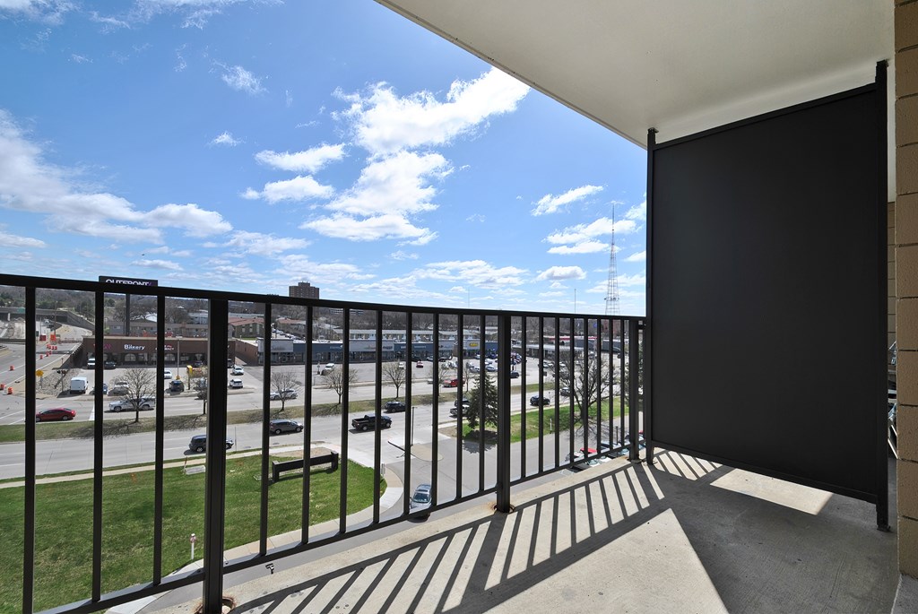 A balcony with a black railing overlooks a parking lot.
