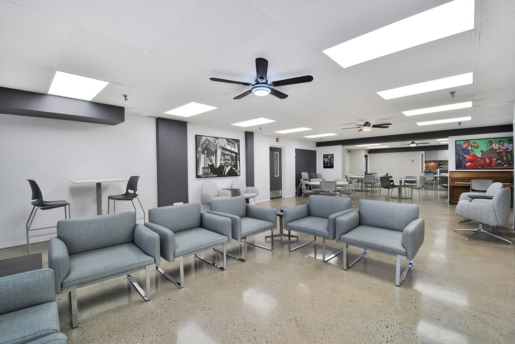A room with grey couches and a ceiling fan.