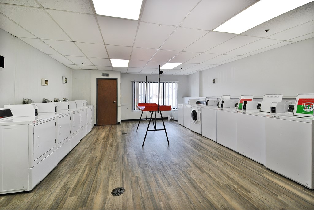 A laundromat with a red chair in the middle of the room.
