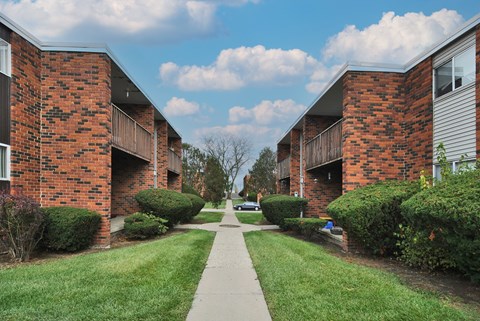 A long, narrow walkway separates two rows of red brick apartment buildings.