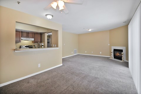 A spacious living room with a fireplace and a ceiling fan.