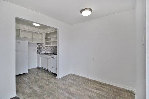 A kitchen with white cabinets and a refrigerator is visible from the living room.