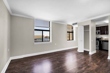 an empty living room with a window and a kitchen