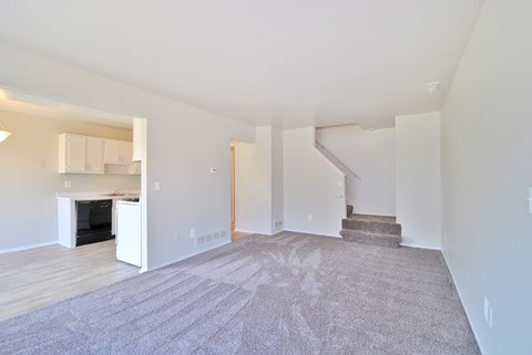 A spacious living room with a fireplace and a staircase.