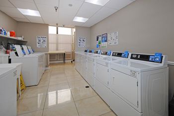 a row of washing machines in a laundry room with washers and dryers