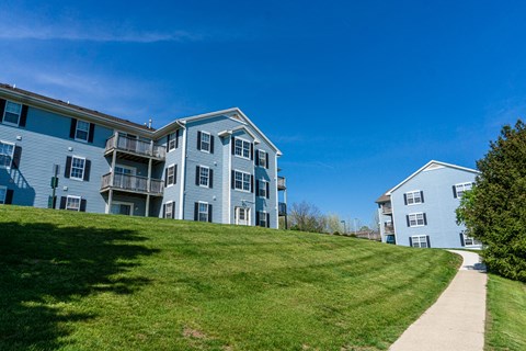 Sidewalk and apartment building on hill with view. Apartments for rent in Kalamazoo, MI near WMU Western Michigan University