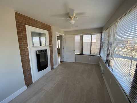 a living room with a brick fireplace and a ceiling fan