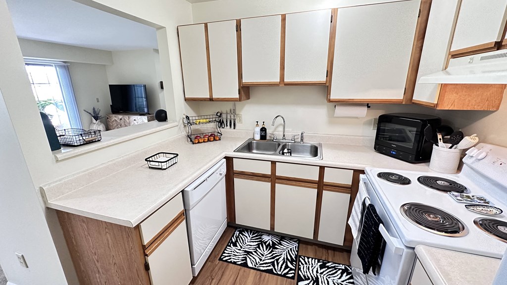 an empty kitchen with white cabinets and a stove and sink