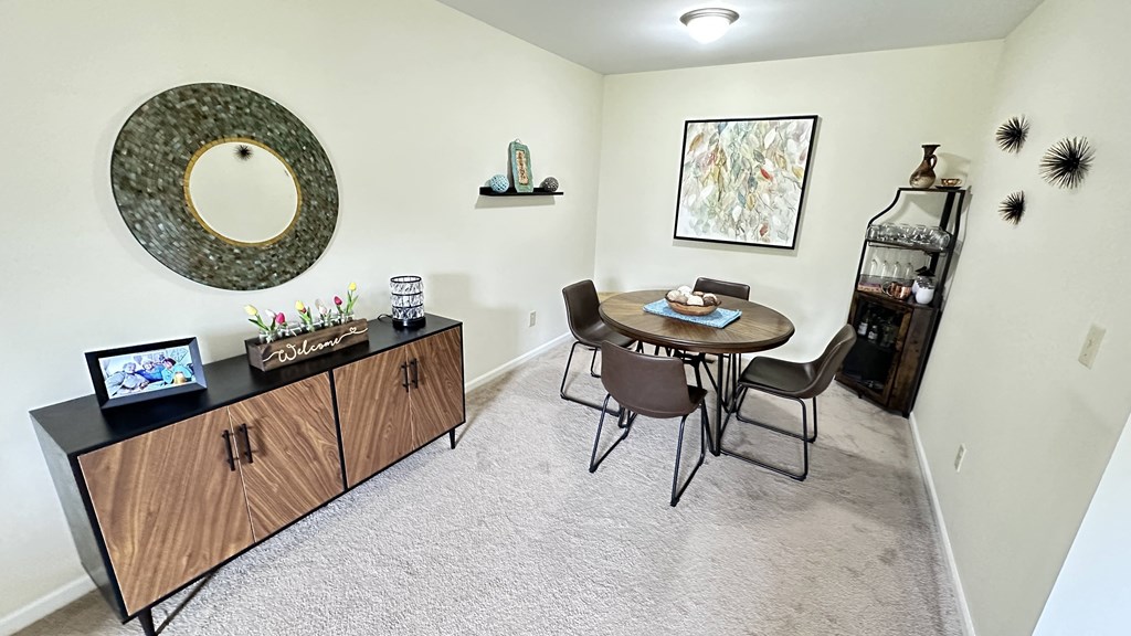 a dining room with a table and chairs and a wall mounted mirror