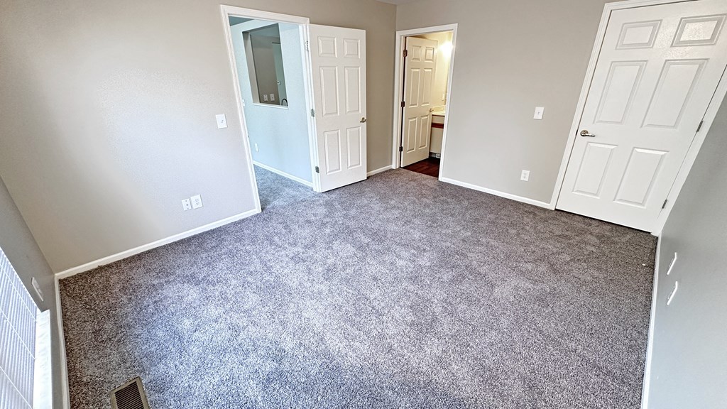 an empty room with a carpeted floor and white doors