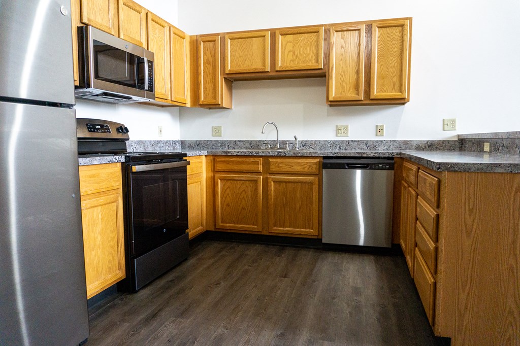 an empty kitchen with wooden cabinets and stainless steel appliances