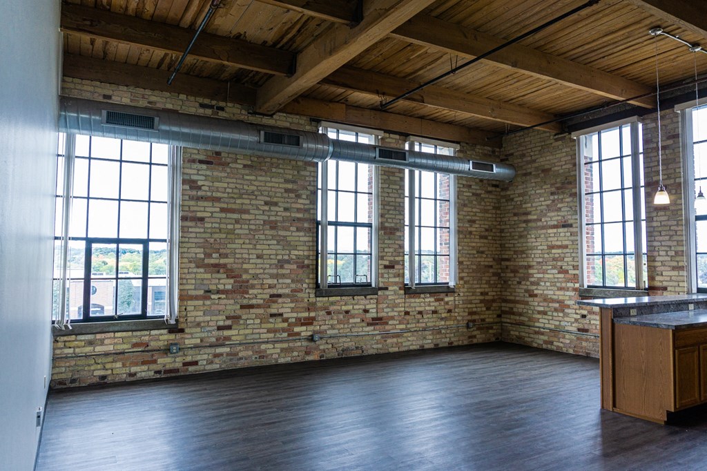 an empty room with a brick wall and large windows