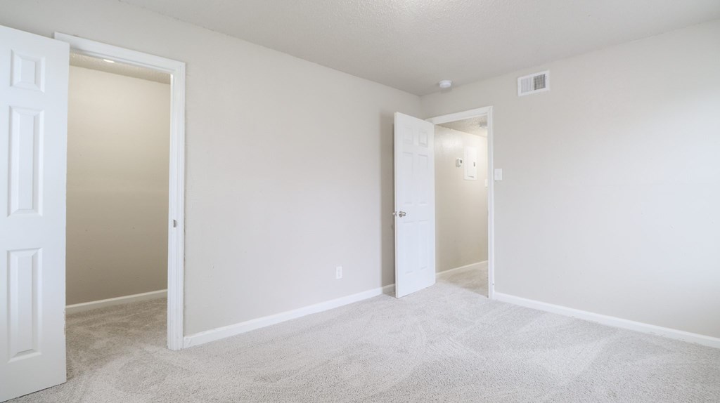 A white room with two doors and carpeted floor.