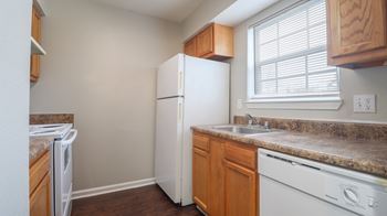 A kitchen with a white refrigerator, a washer and dryer, and a dishwasher.