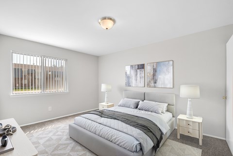 A bedroom with a large bed and two lamps.
