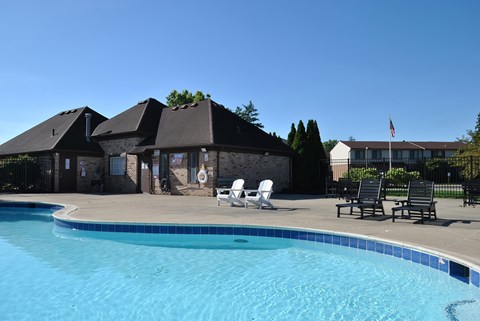 A swimming pool in front of a house with a flag on the house.
