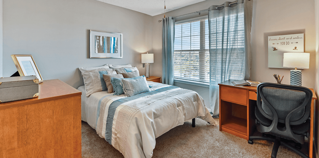 a bedroom with a bed and a desk and a window