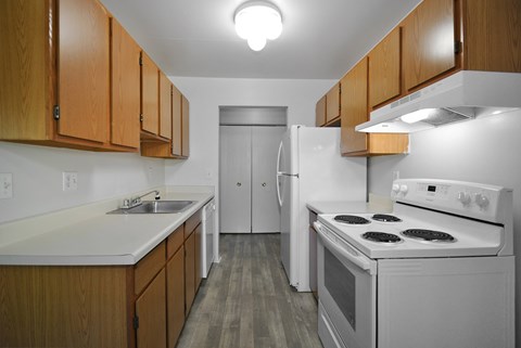A kitchen with white appliances and wooden cabinets.
