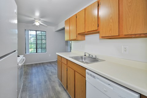 A kitchen with wooden cabinets and a white dishwasher.