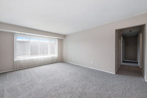 the living room of an apartment with a large window and carpet