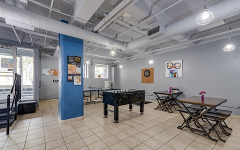 a room with a foosball table and tables with chairs at The Lofts at 5 Lyon, in downtown Grand Rapids, MI