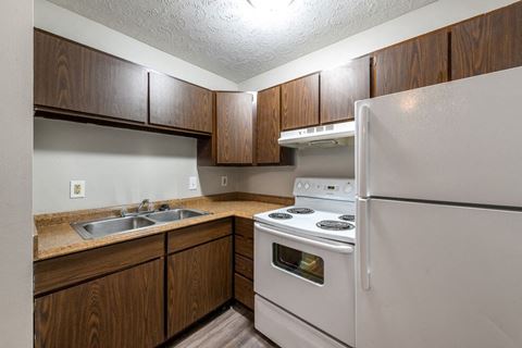 a kitchen with white appliances and wooden cabinets at Timber Creek Apartments in Niles, Ohio