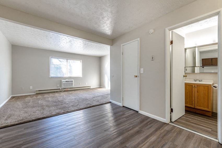 A spacious living room with a kitchen in the background at Timber Creek Apartments in Niles, Ohio