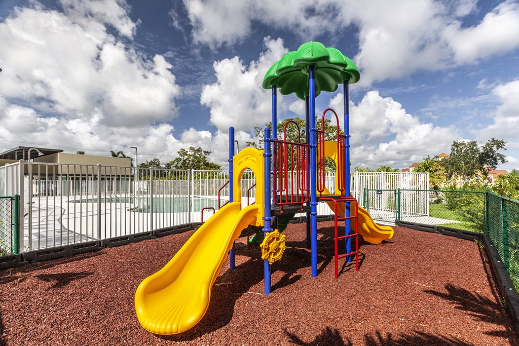 a playground with a slide and umbrella at a park